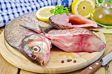 Image showing Bream raw on a round board with a knife and oil