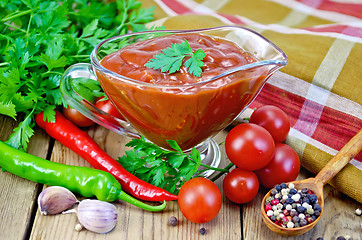 Image showing Ketchup in a glass gravy boat with vegetables on the board