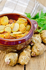 Image showing Jerusalem artichokes roasted in a clay pot on a board