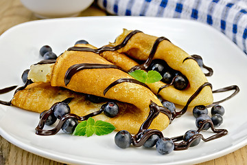 Image showing Pancakes with blueberries and chocolate syrup on the board