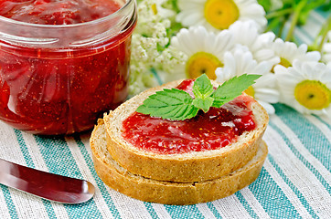 Image showing Bread with strawberry jam and daisies on a napkin