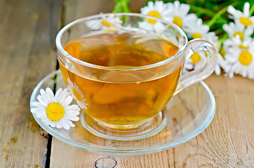 Image showing Herbal chamomile tea in a glass cup on a board