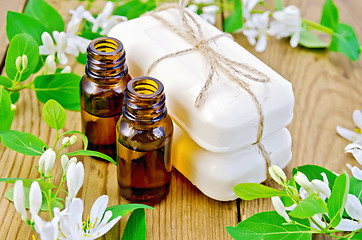 Image showing Oil and white soap with flowers of honeysuckle