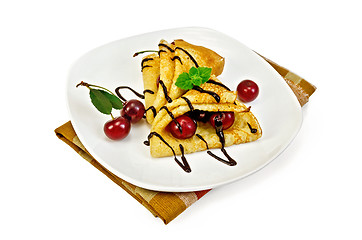 Image showing Pancakes with cherry and chocolate syrup on a napkin