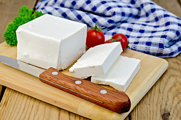 Image showing Feta cheese on a board with a knife and tomato