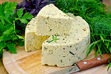 Image showing Cheese round homemade with herbs and knife on board