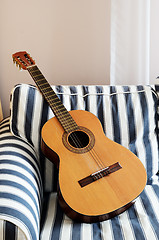 Image showing acoustic guitar on a striped couch