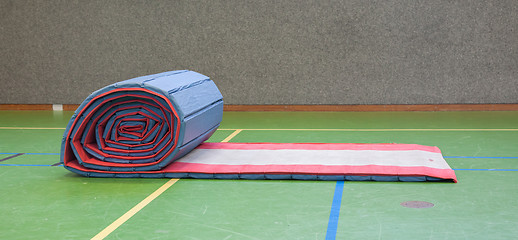 Image showing Very old long mat on a green court