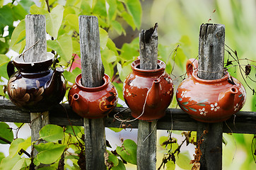 Image showing four ceramic teapot on a wooden fence