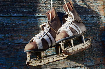 Image showing vintage pair of mens  ice skates hanging on a wooden wall with c