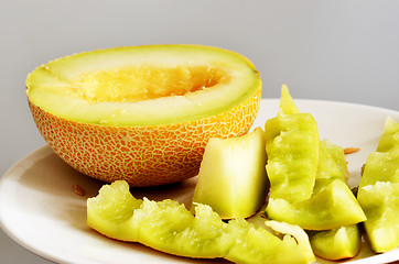 Image showing half of ripe melonand peels on a plate, still life