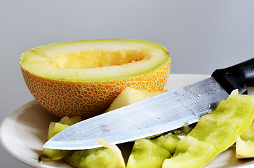 Image showing still life, half of ripe melon, knife and peels on a plate