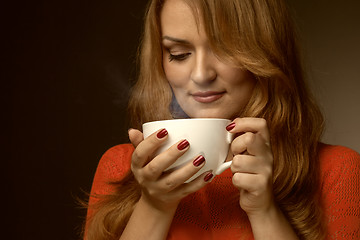 Image showing woman holding hot cup and smiles