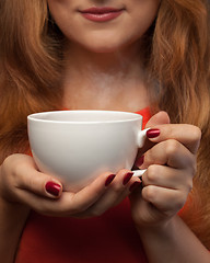 Image showing woman holding hot cup and smiles