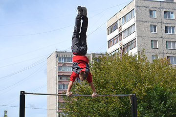 Image showing The man goes in for sports on a horizontal bar in a house yard