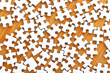 Image showing White puzzle on wooden background