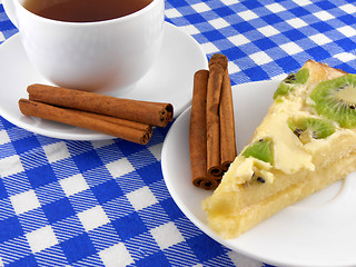 Image showing A cup of tea and a piece of tasty creamy cake with cinnamon