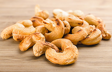 Image showing A handful of roasted cashew nuts on wood background