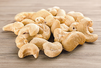 Image showing A handful of row cashew nuts on wood background