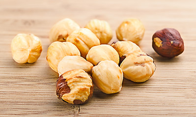 Image showing A pile of shell-less hazelnuts, isolated on textural wood backgr