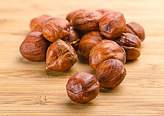 Image showing A pile of shell-less hazelnuts, isolated on textural wood backgr