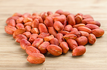 Image showing heap of roasted peanuts on the wooden background