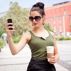 Image showing attractive young woman with smartphone and sunglasses outdoor