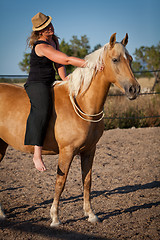 Image showing young woman training horse outside in summer