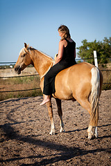 Image showing young woman training horse outside in summer