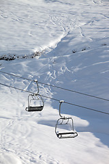 Image showing Two chair-lift with snowdrift and off-piste slope in sun morning