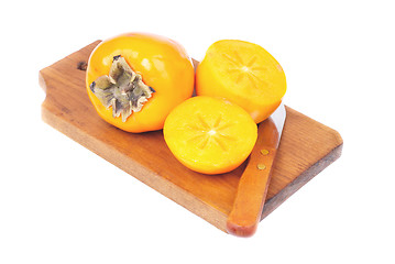 Image showing Persimmon fruit whole and sliced on cutting  board isolated on white background