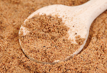 Image showing Nutmeg ground (Myristica fragrans) texture and wooden spoon, full frame background. Used as a spice and medicine. 