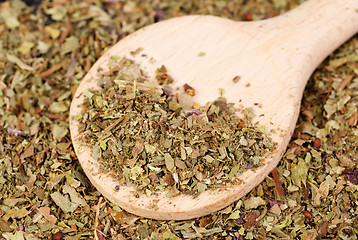 Image showing Pile of ground dried Basil (Sweet Basil) as background with wooden spoon. Used as a spice in culinary herb all over the world. The plant is also used in medicine. 
