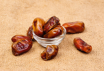 Image showing dried dates on glass bowl on canvas background
