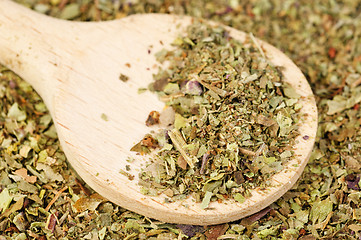 Image showing Pile of ground dried Basil (Sweet Basil) as background with wooden spoon. Used as a spice in culinary herb all over the world. The plant is also used in medicine. 