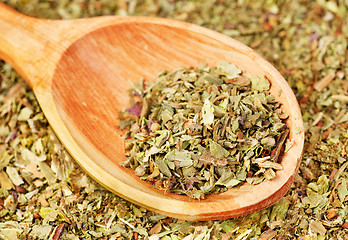 Image showing Pile of ground dried Basil (Sweet Basil) as background with wooden spoon. Used as a spice in culinary herb all over the world. The plant is also used in medicine. 