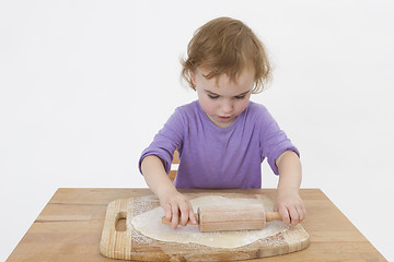 Image showing cute curly child rolling out dough