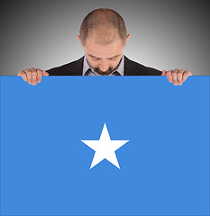 Image showing Smiling businessman holding a big card or flag