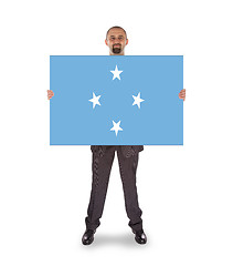 Image showing Smiling businessman holding a big card or flag