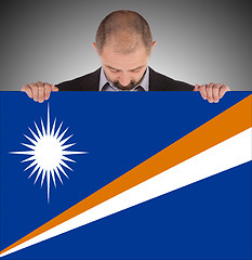 Image showing Smiling businessman holding a big card or flag