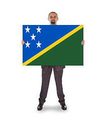 Image showing Smiling businessman holding a big card or flag