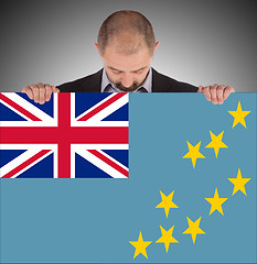 Image showing Smiling businessman holding a big card or flag