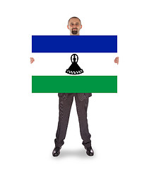 Image showing Smiling businessman holding a big card or flag