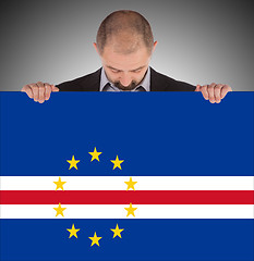 Image showing Smiling businessman holding a big card or flag