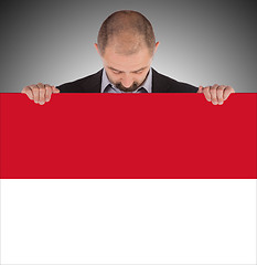 Image showing Smiling businessman holding a big card or flag