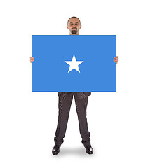 Image showing Smiling businessman holding a big card or flag