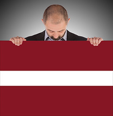 Image showing Smiling businessman holding a big card or flag