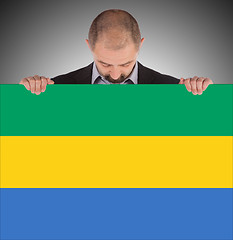 Image showing Smiling businessman holding a big card or flag