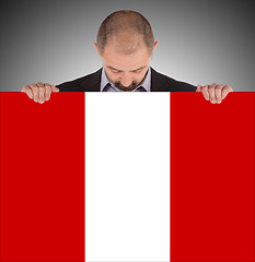 Image showing Smiling businessman holding a big card or flag