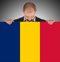 Image showing Smiling businessman holding a big card or flag